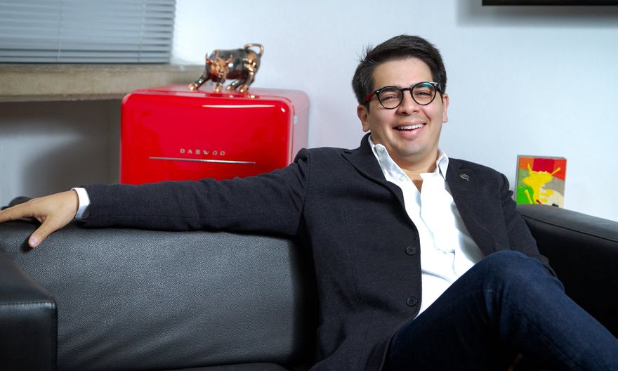 Christian Solitario on the sofa in his office; behind him, a bronze bull on a red fridge.