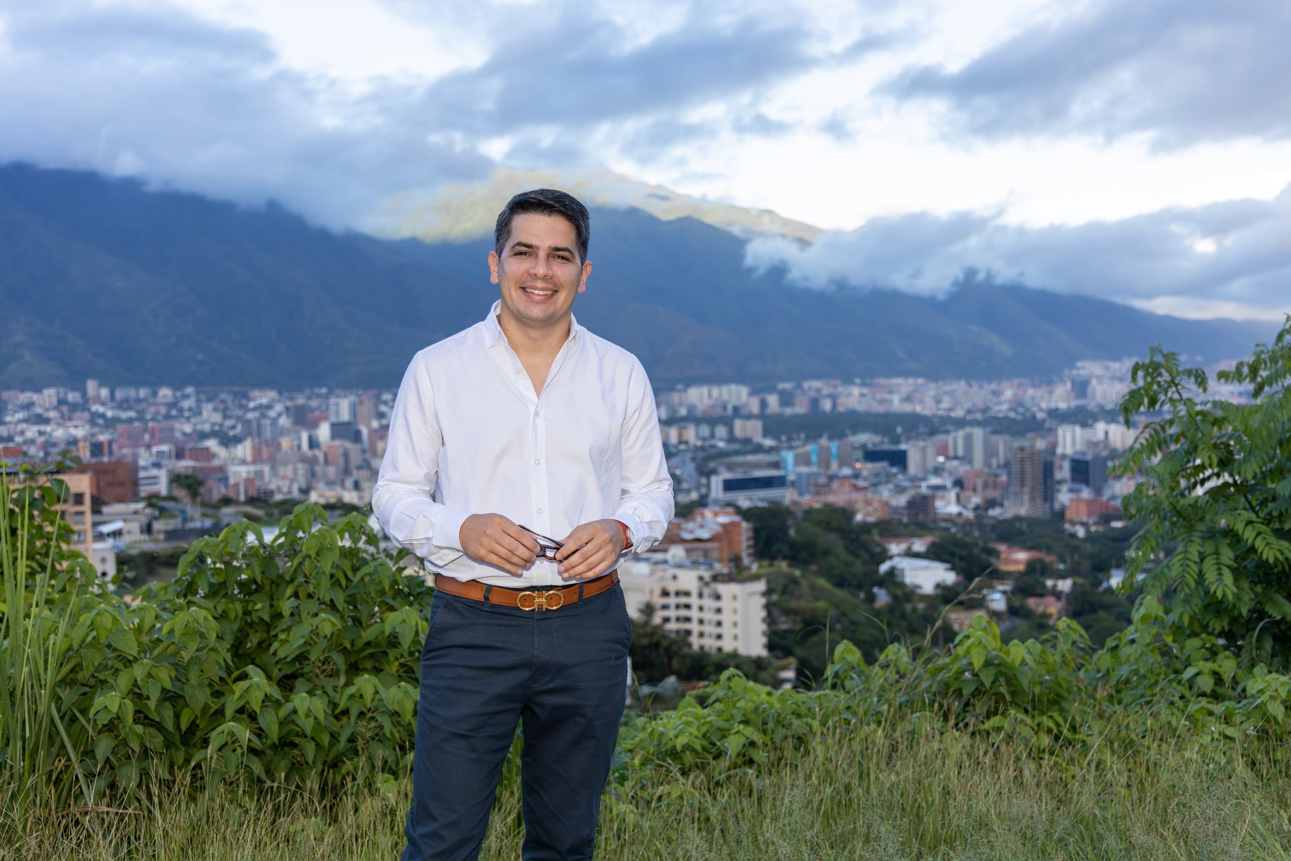 Christian Solitario, de camisa blanca, con Caracas y el Ávila detrás.